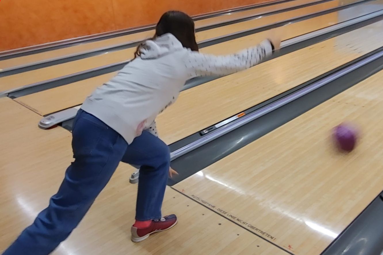 Eine Teilnehmerin wirft den lila Bowlingball